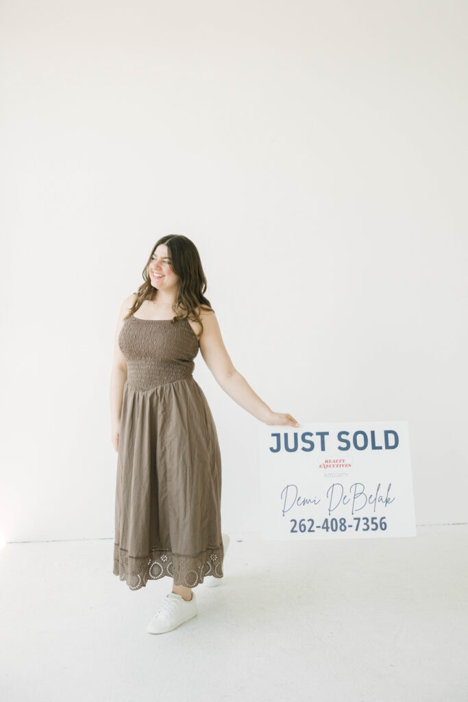 Real estate agent posing with “Sold” sign during branding photoshoot in Milwaukee studio