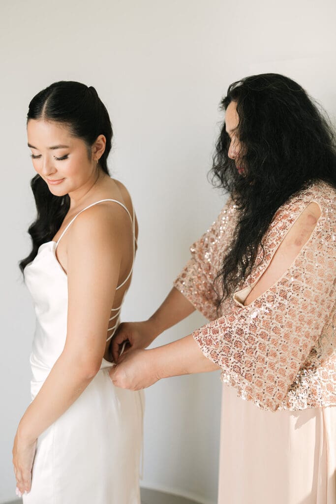 bride putting on dress during Santorini wedding morning